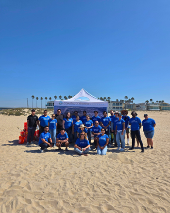 A sponsored beach cleanup where all participants are in a blue shirt in front of the CCA canopy.