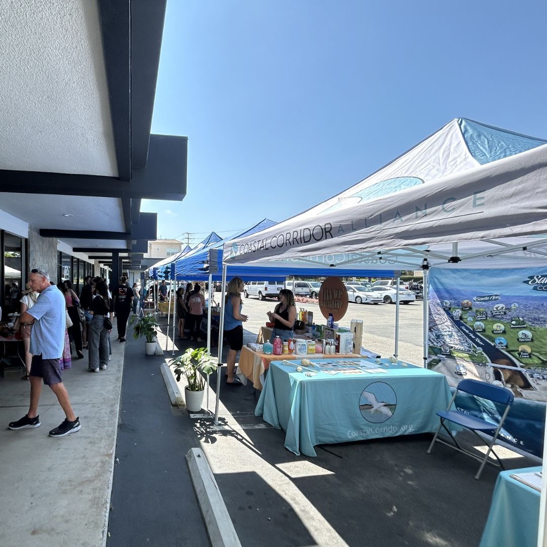 A photograph of the CCA booth and other booths in a row with people mingling about.