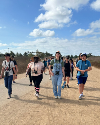 A group of people with binoculars are walking on a trail.